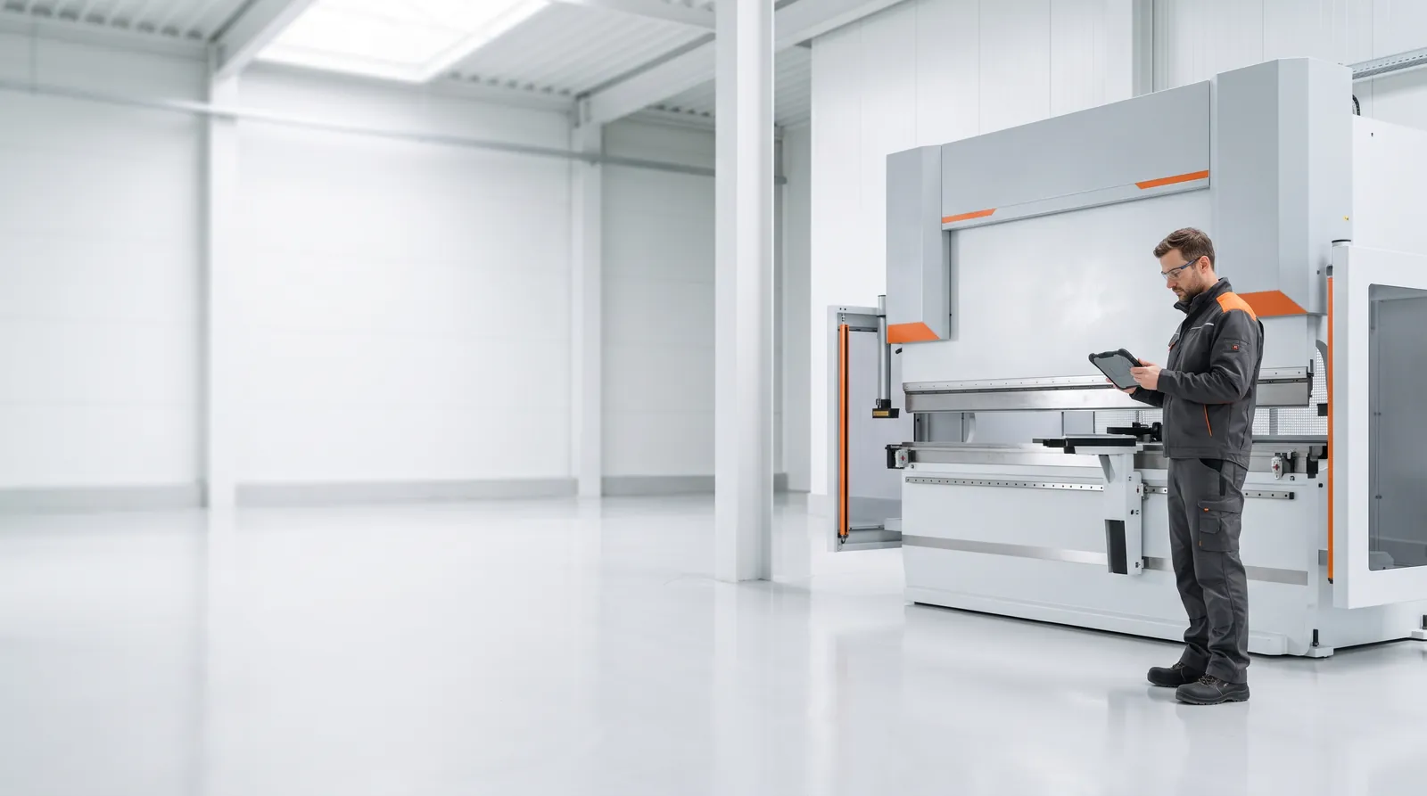 A technician with a diagnostic tablet beside a CNC press brake in a bright factory